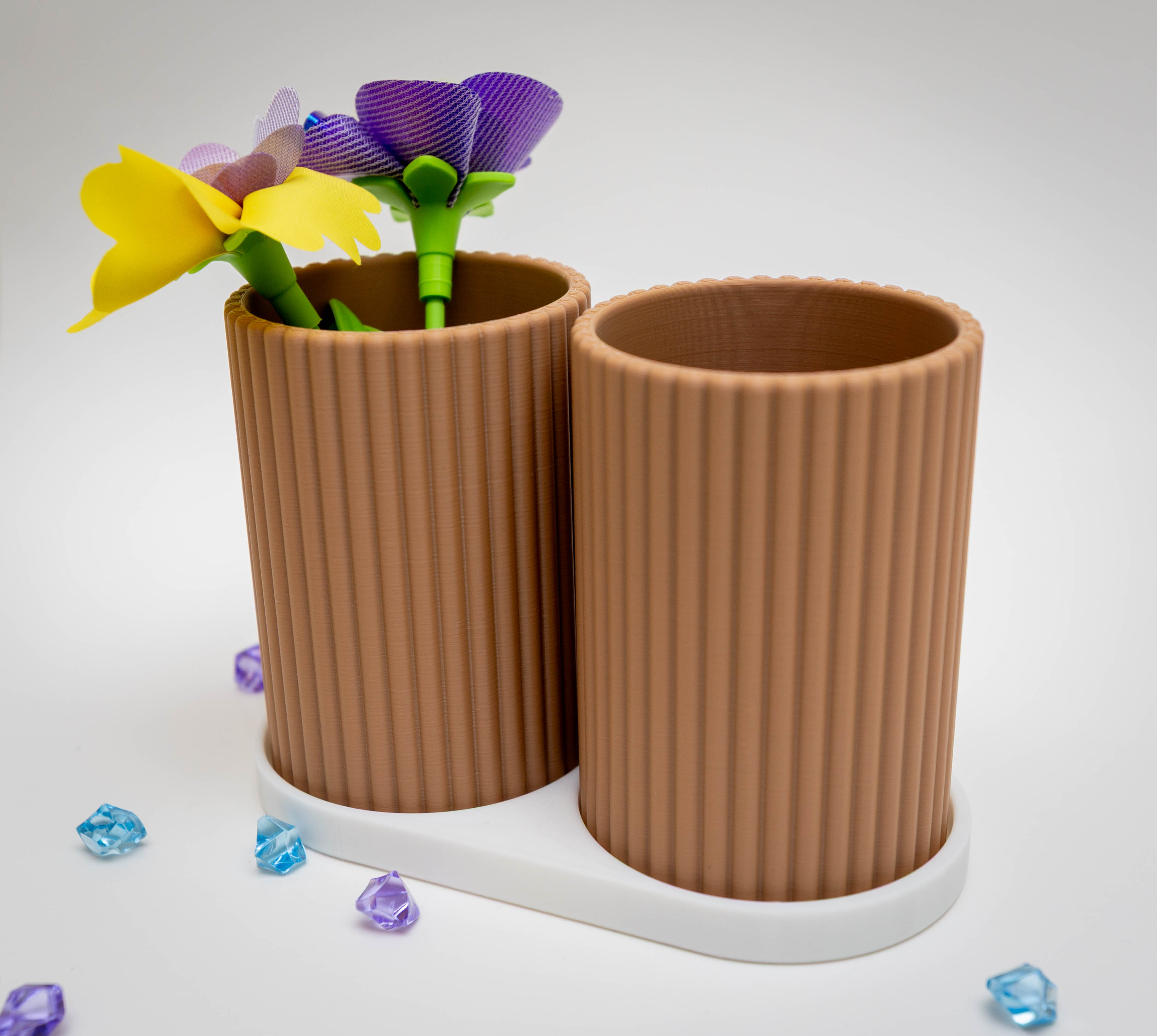Two ribbed cylinder vases with colorful flowers and gems